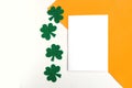 Happy St. PatrickÃ¢â¬â¢s Day. Three leaf clover and white mockup blank on white and orange background.